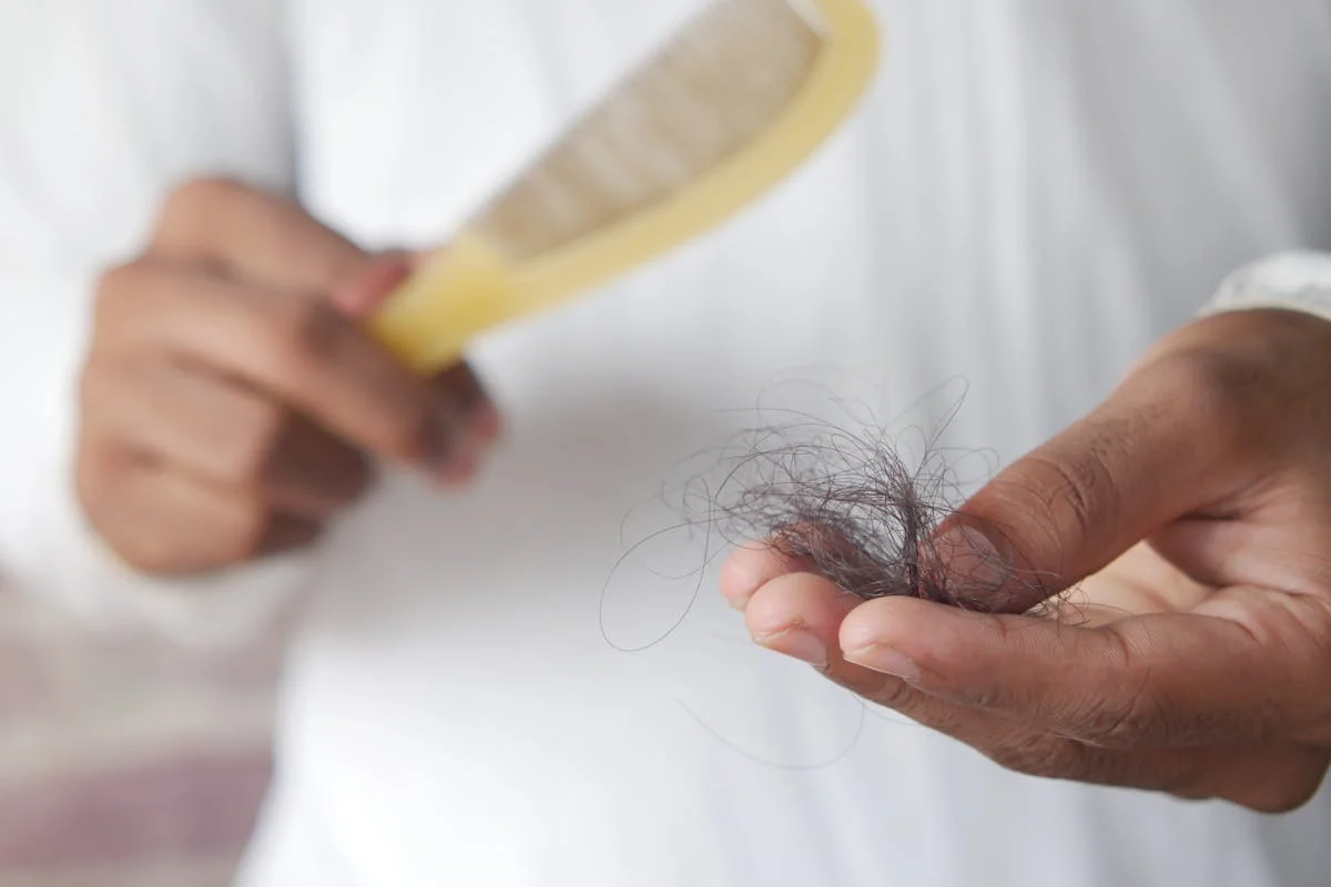 Peine con cabellos caídos sobre fondo claro, ilustrando la caída de pelo asociada al tratamiento con Wegovy y Ozempic