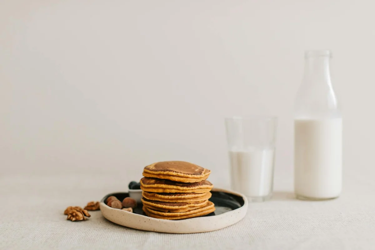 Cuatro tortitas de avena apiladas con frutos rojos sobre un plato blanco, desayuno alto en proteínas