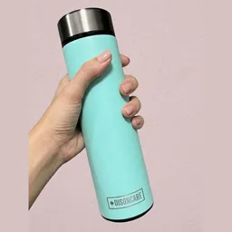 Mano sujetando la nevera portátil DISONCARE, un termo cilíndrico turquesa con tapa metálica, sobre una pared rosa
